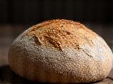 A dark, rustic whole wheat sourdough loaf with a dense crumb.